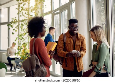 Group Of Happy College Friends Using Mobile Phone In A Hallway. Focus Is On Black Male Student.  