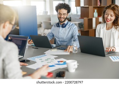 Group Of Happy Diverse Coworkers Analyzing Sales Report While Working Together In The Office