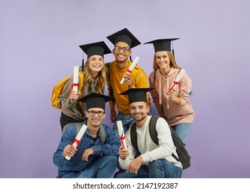 Group Of Happy Diverse Mixed Race Multiethnic Students With Backpacks, In Mortarboard Graduate Hats Holding Diploma Scrolls, Looking At Camera And Smiling. University Education And Graduation Concept