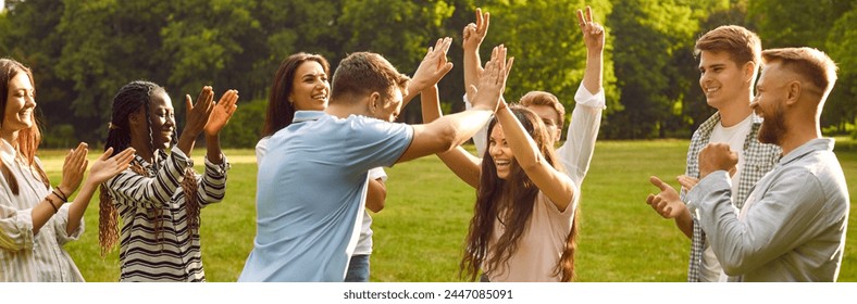 Group of happy diverse people celebrate victory in outdoor team game in green summer park. Joyful young man and woman give each other high five while their friends clap hands and cheer - Powered by Shutterstock