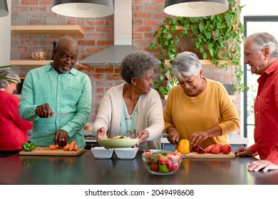 Group Of Happy Diverse Senior Male And Female Friends Cooking Together At Home. Cooking And Socialising With Friends At Home.