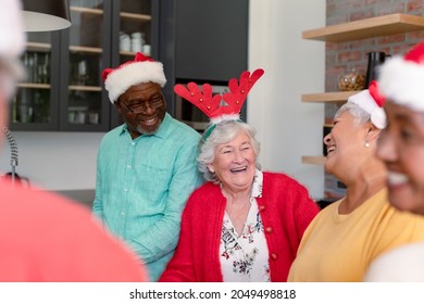 Group of happy diverse senior male and female friends in christmas hats cooking together in kitchen. christmas festivities, celebrating at home with friends. - Powered by Shutterstock