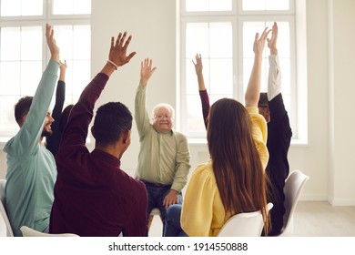 Group of happy diverse young and mature people in casual clothes sitting on chairs in circle and raising hands, approving of good idea and voting for useful suggestion in community club meeting - Powered by Shutterstock