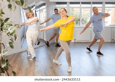 Group of happy elderly pensioners learning to dance latin dances in dance studio - Powered by Shutterstock