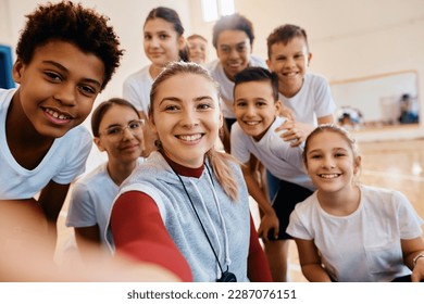 Group of happy elementary students and their sports teacher taking selfie on physical education class at school gym. - Powered by Shutterstock