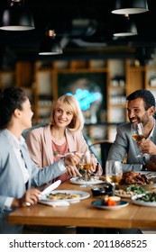 Group Of Happy Entrepreneurs Communicating While Having Business Lunch In A Restaurant. 