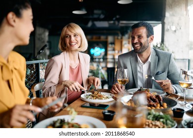 Group of happy entrepreneurs communicating while enjoying in business lunch in a restaurant.