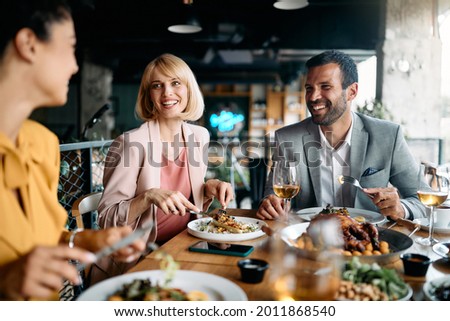 Group of happy entrepreneurs communicating while enjoying in business lunch in a restaurant.