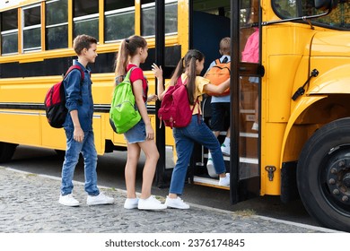 Group of happy excited children boarding yellow school bus, diverse kids with backpacks getting in schoolbus, boys and girls going home together after lessons, climbing stairs of vehicle - Powered by Shutterstock