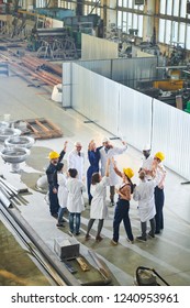 Group Of Happy  Factory Workers Meeting With Management In Large Industrial Workshop, Copy Space