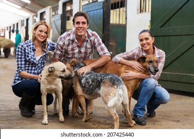 Group Of Happy Farm Workers With Pet Dogs In Stables