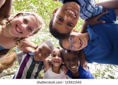 Group Of Happy Female And Male Kids Having Fun And Hugging Around The Camera. Low Angle View