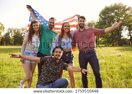 Group of happy friends with American flag in countryside. Young patriotic people with national banner. Independence Day
