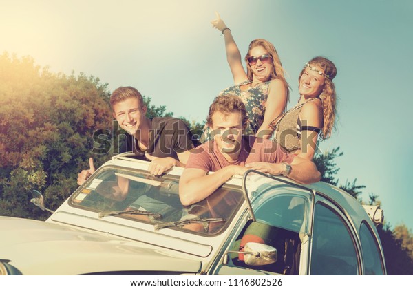 Group of
happy friends in a car at sunset in
summer.