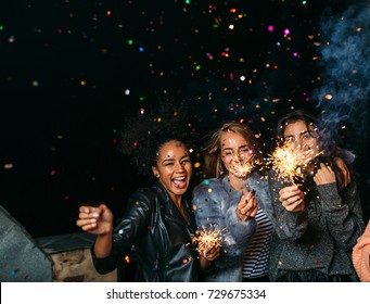 Group of happy friends celebrating new year's eve with confetti and sparklers - Powered by Shutterstock