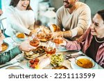 Group of happy friends clinking rose wine glasses - Smiling young people enjoying dinner party at home - Life style concept with guys and girls eating meal and drinking alcohol - Focus on left glass