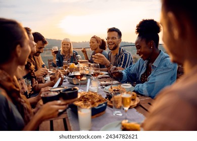 Group of happy friends communicating while gathering for meal on a patio at sunset.  - Powered by Shutterstock