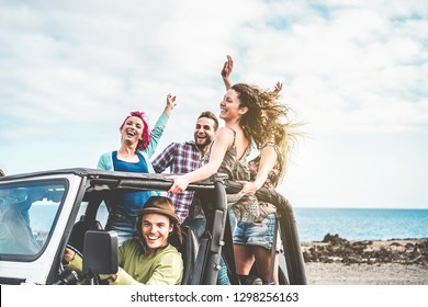 Group of happy friends doing excursion on desert in convertible 4x4 car - Young people having fun traveling together - Friendship, tour, youth lifestyle and vacation concept - Focus on right girl face - Shutterstock ID 1298256163
