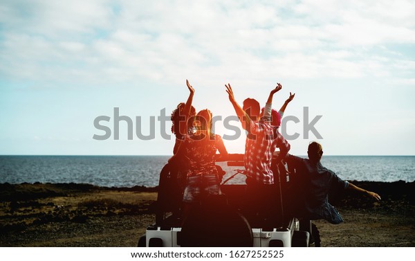 Group of happy friends doing excursion on desert\
in convertible 4x4 car - Young people having fun traveling together\
- Friendship, tour, youth, lifestyle and vacation concept - Focus\
on guys bodies