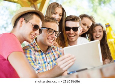 Group Of Happy Friends Drinking And Having Fun With Tablet In Pub Garden