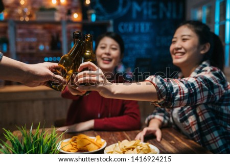 Group of happy friends drinking and toasting beer at brewery bar restaurant in late night. Friendship concept with young people having fun together at cool vintage pub. focus on hands bottle alcohol