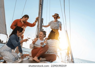 Group of happy friends drinking wine and relaxing on the sailboat during sailing in sea. - Powered by Shutterstock