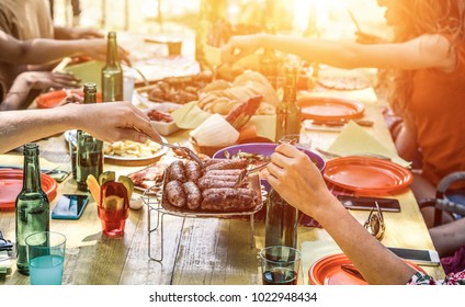 Group Of Happy Friends Eating And Drinking Beers At Barbecue Dinner On Sunset Time - Adult People Having Meal Together Outdoor - Focus On Fork Sausages - Summer Lifestyle, Food And Friendship Concept