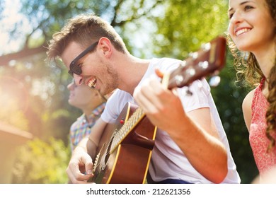 Group of happy friends with guitar having fun outdoor - Powered by Shutterstock