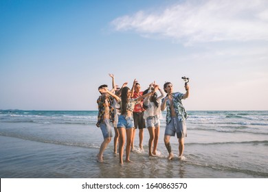 A group of happy friends having enjoy playing selfies on the beach amid the blue sky. - Powered by Shutterstock