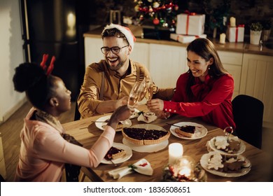 Group of happy friends having fun and toasting with Champagne at dining table on Christmas Eve.  - Shutterstock ID 1836508651
