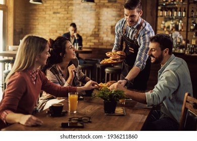 Group of happy friends having fun while waiter is serving them food in a pub.  - Powered by Shutterstock