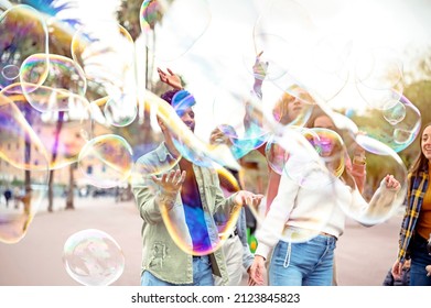 Group of happy friends having fun with soap bubbles in the town square - Millennial guys and girls having fun around the streets - University students on travel vacations - Focus on the bubbles - Powered by Shutterstock