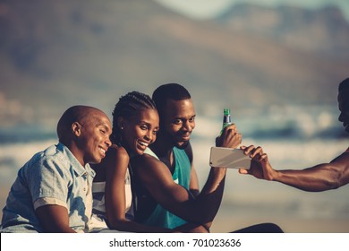 Group of happy friends having fun together and taking selfie using mobile phone. Self portrait at beach party.