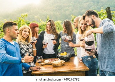 Group of happy friends having fun outdoors drinking red wine - Young people eating local fresh food at grape harvesting in farmhouse vineyard winery - Youth friendship concept on a vivid warm filter - Powered by Shutterstock