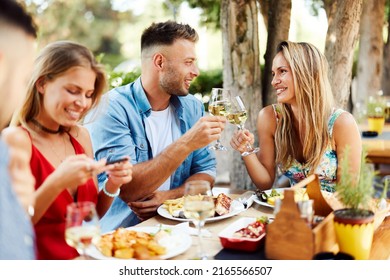 Group of Happy friends having lunch in the restaurant and toast with white wine during a sunny summer day - Shutterstock ID 2165566507