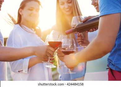 Group of happy friends having red wine on the beach. Sunset beach party - Powered by Shutterstock