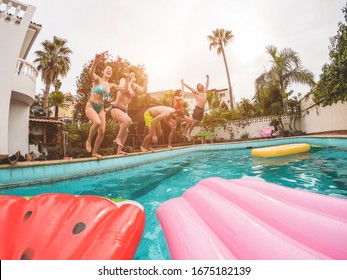 Group Of Happy Friends Jumping Inside Pool At Sunset - Young Diverse Culture People Having Fun In Tropical Vacation - Holiday, Youth And Friendship Concept - Focus On Guys Bodies