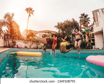 Group of happy friends jumping in pool at sunset time - Crazy young people having fun making party in exclusive tropical house - Holidays, summer, vacation and youth lifestyle concept