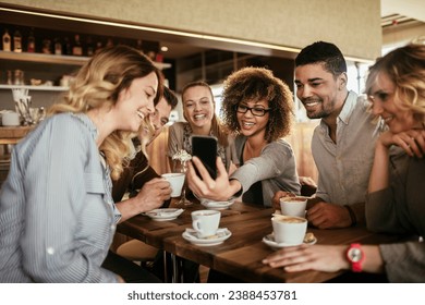 Group of Happy friends looking at smartphone in cafe together - Powered by Shutterstock