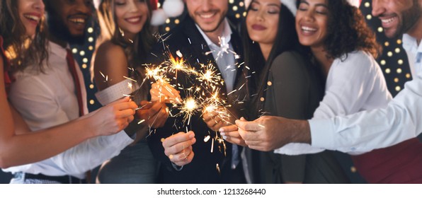 Group of happy friends in New Year eve with sparkling bengal lights, panorama, closeup