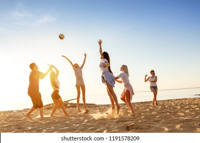 Group of happy friends plays with ball at sunset beach. Weekend activity concept - Powered by Shutterstock