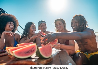 Group Of Happy Friends Relaxing And Eating Water Melon While Having Boat Tour In Mediterranean Sea