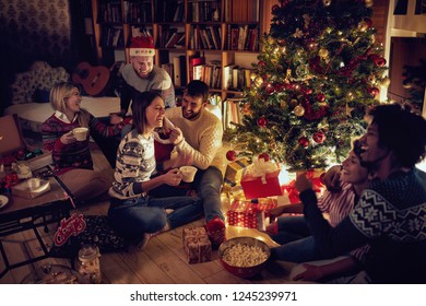 Group of happy friends sitting next to a Christmas tree, and having fun.