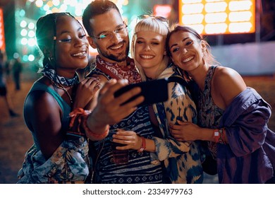 Group of happy friends taking selfie during live performance on summer music festival at night. - Powered by Shutterstock