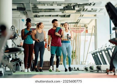Grupo de amigos felices hablando después de hacer ejercicio en un gimnasio. Copiar espacio.