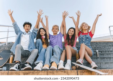 Group of happy friends, teenagers boys and girls in colorful t shirts holding hands up celebration summer vacation sitting on stairs - Powered by Shutterstock