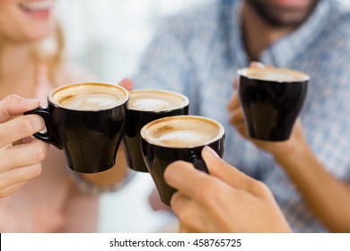 Group Of Happy Friends Toasting Cup Of Coffee In Cafe