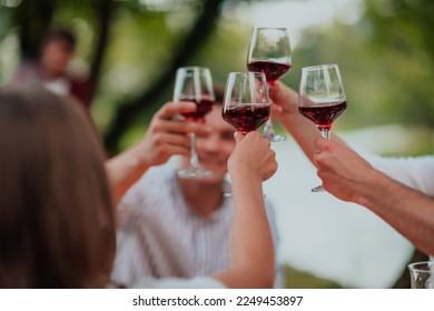 Group of happy friends toasting red wine glass while having picnic french dinner party outdoor during summer holiday vacation near the river at beautiful nature - Powered by Shutterstock