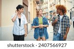 Group of happy friends, two guys and girl, walking together, talking and laughing, feeling free