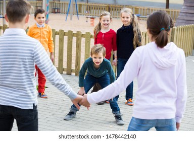 Group Of Happy Glad Children Playing Red Rover Outdoors